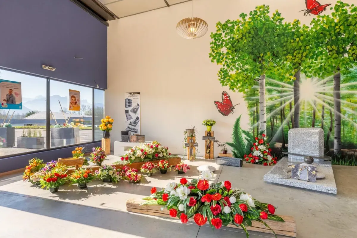 Showroom funéraire avec compositions florales et monument en granit.